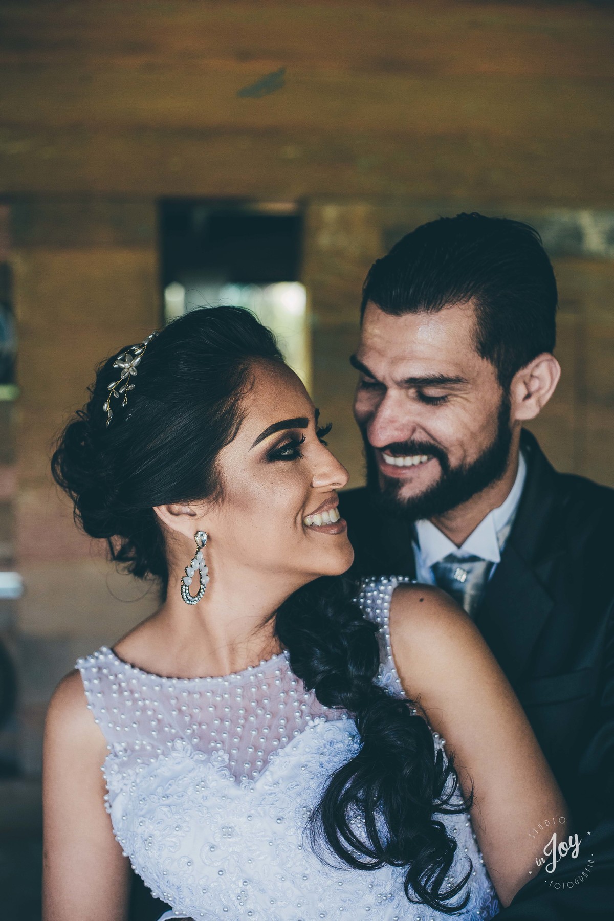 fotografia de casamento do casam que está se abraçando dentro de uma casa com detalhes de madeira