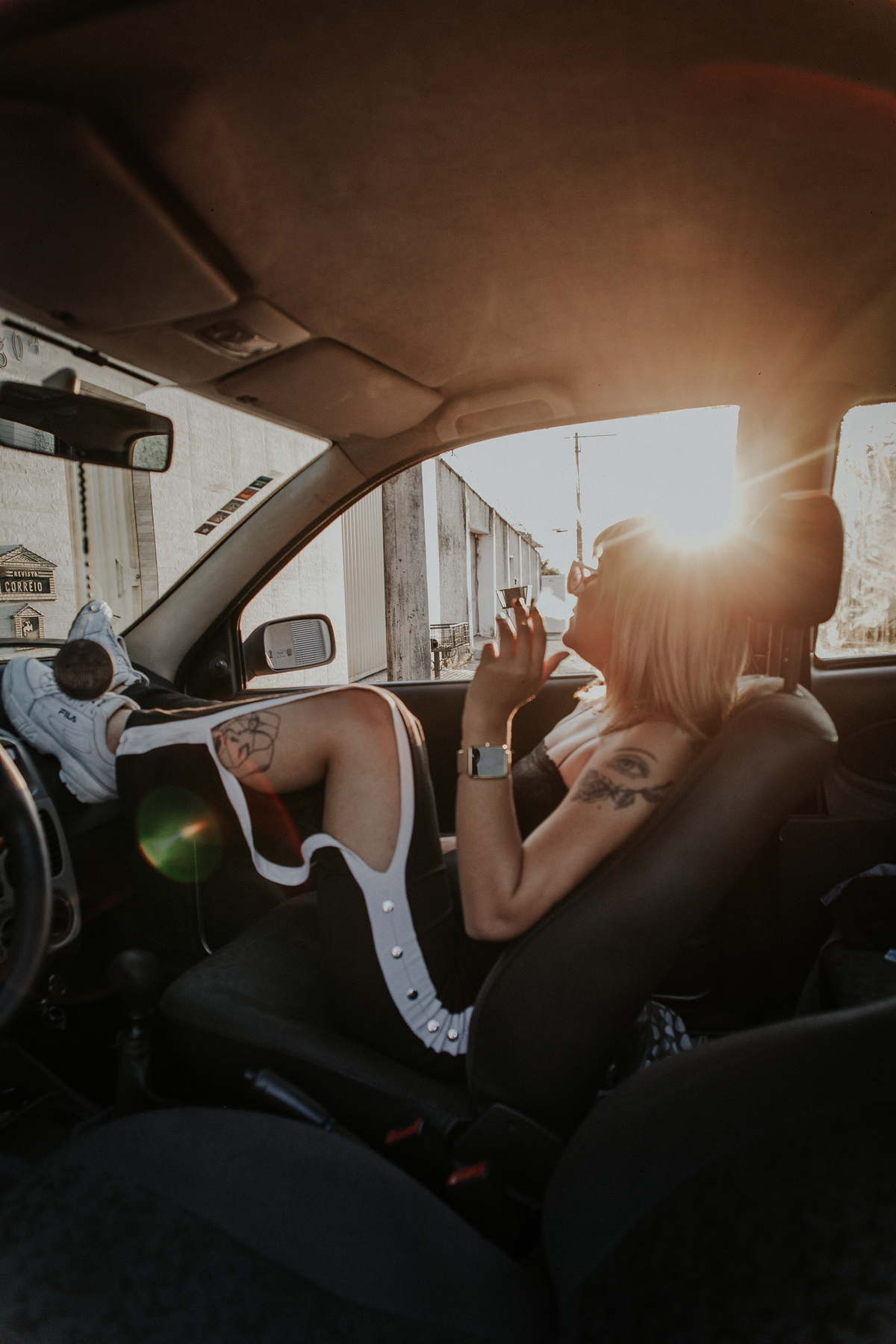 ensaio feminino em betim dentro do carro com uma inspiração de look com jaqueta corta vento, calça pantalona e oculos de sol retro
