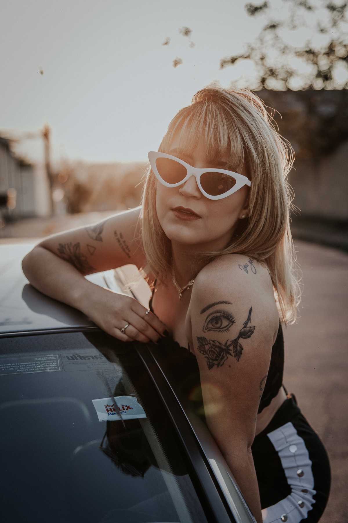 ensaio feminino em betim dentro do carro com uma inspiração de look com jaqueta corta vento, calça pantalona e oculos de sol retro