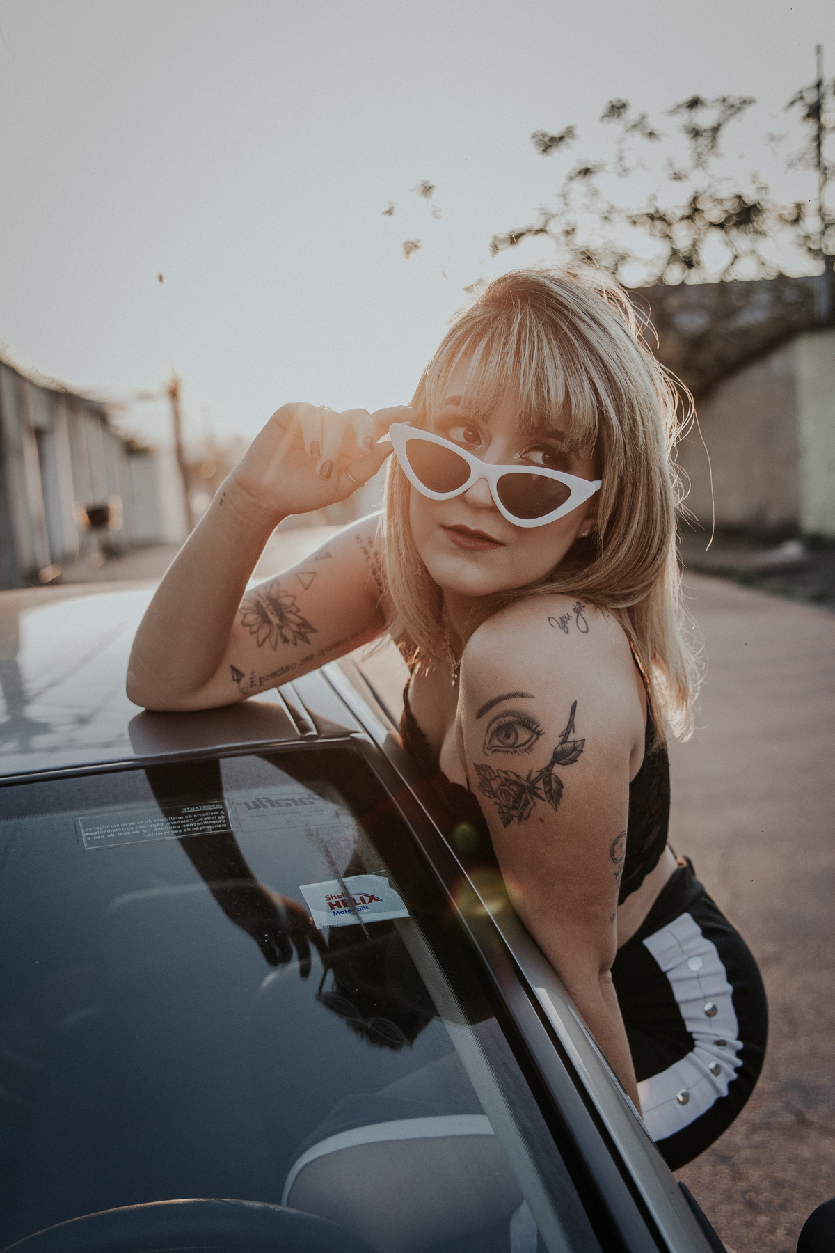 ensaio feminino em betim dentro do carro com uma inspiração de look com jaqueta corta vento, calça pantalona e oculos de sol retro