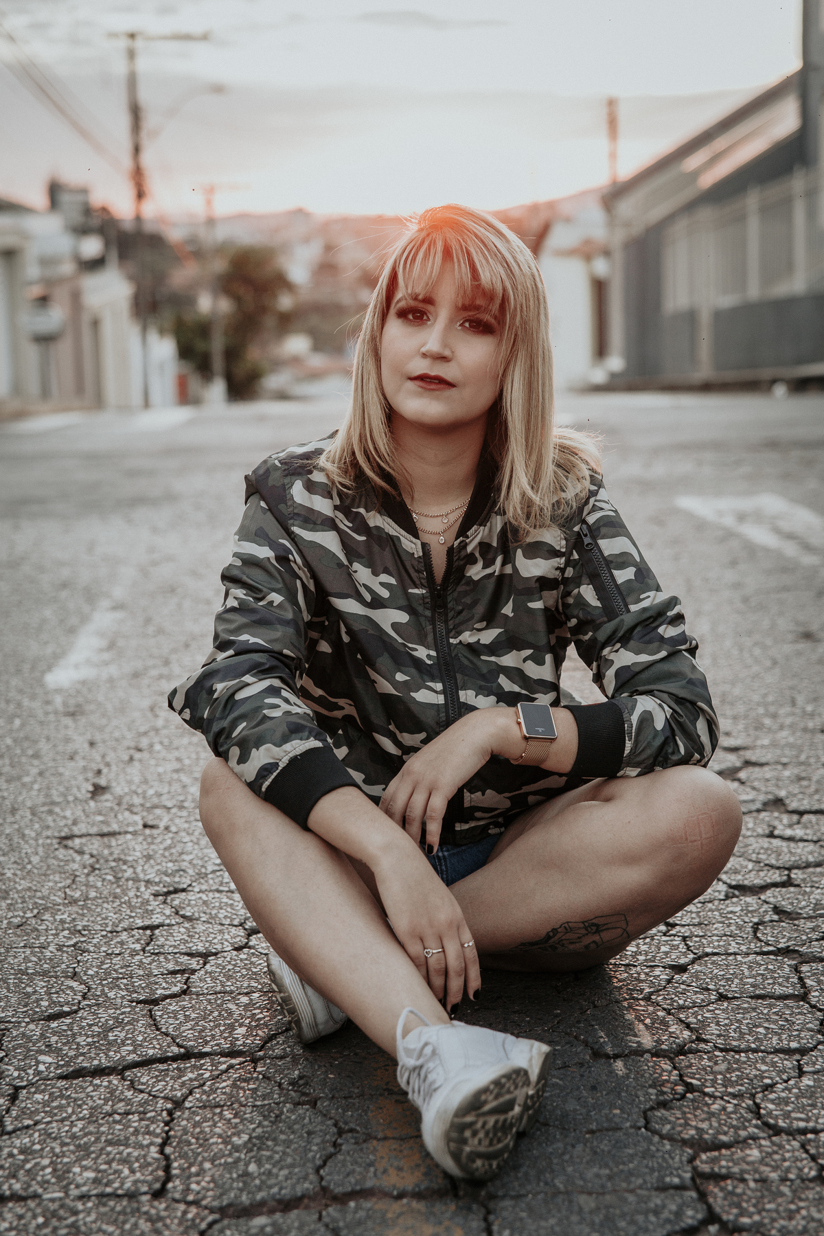 ensaio feminino em betim dentro do carro com uma inspiração de look com jaqueta corta vento camuflada e short jeans com tenis fila branco