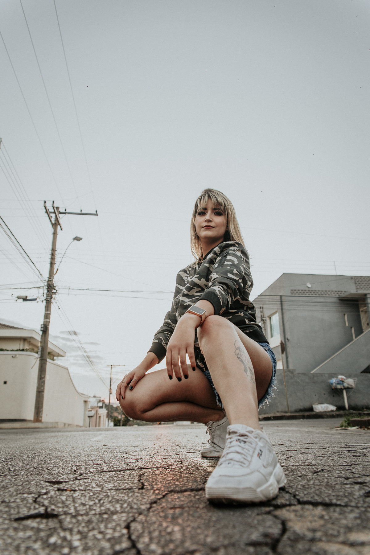 ensaio feminino em betim dentro do carro com uma inspiração de look com jaqueta corta vento camuflada e short jeans com tenis fila branco
