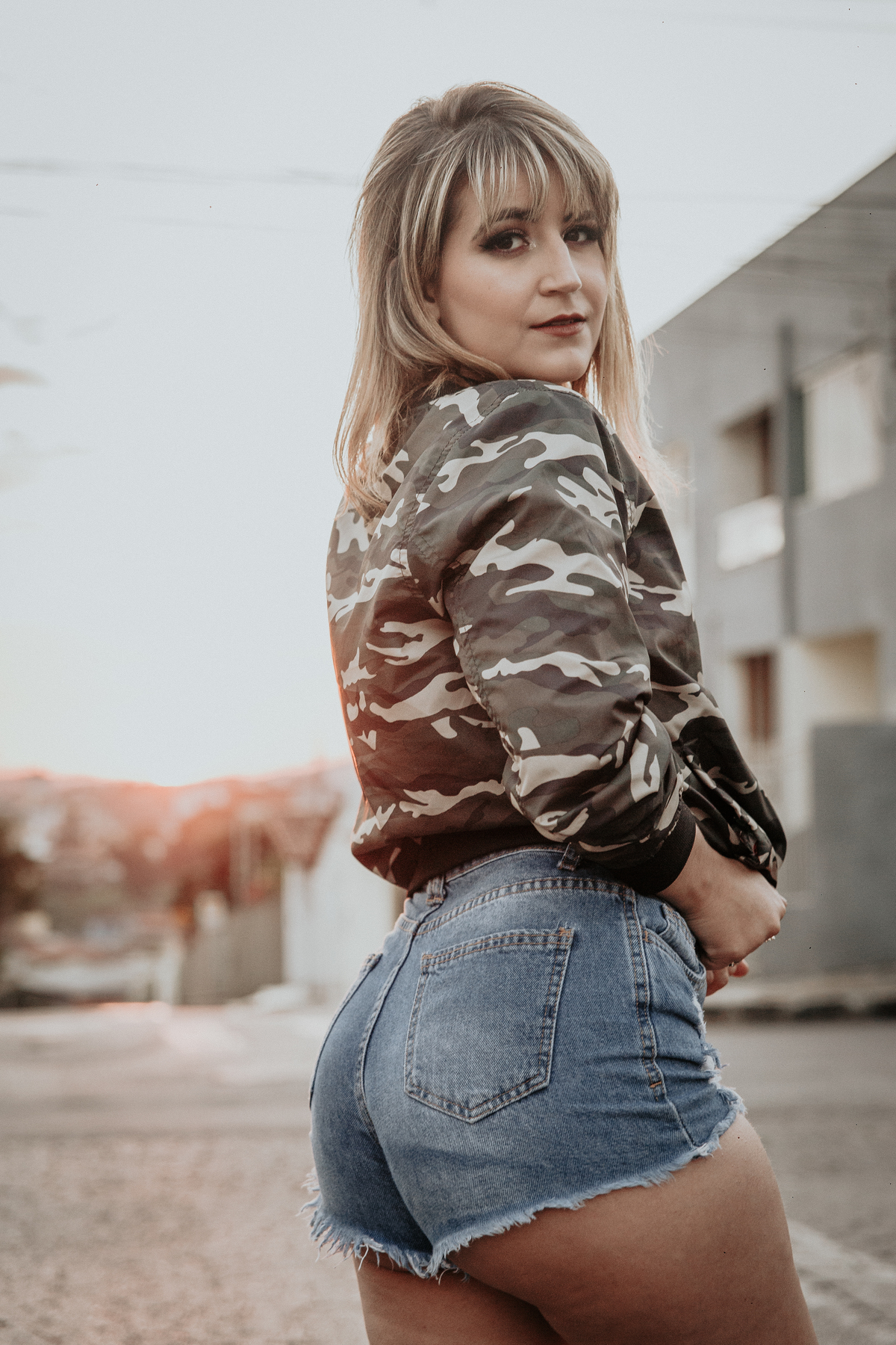 ensaio feminino em betim dentro do carro com uma inspiração de look com jaqueta corta vento camuflada e short jeans com tenis fila branco