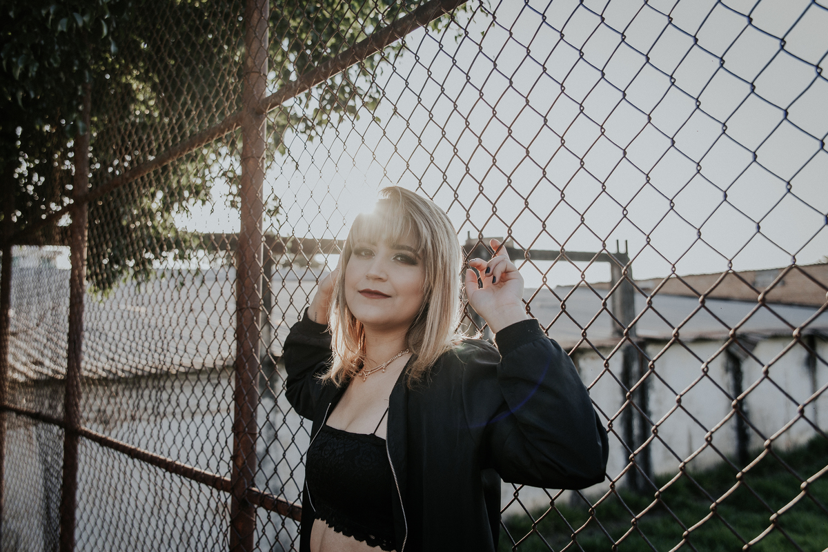 ensaio feminino em betim no estilo street portrait com uma inspiração de look com jaqueta corta vento e calça pantalona. Foto com grade