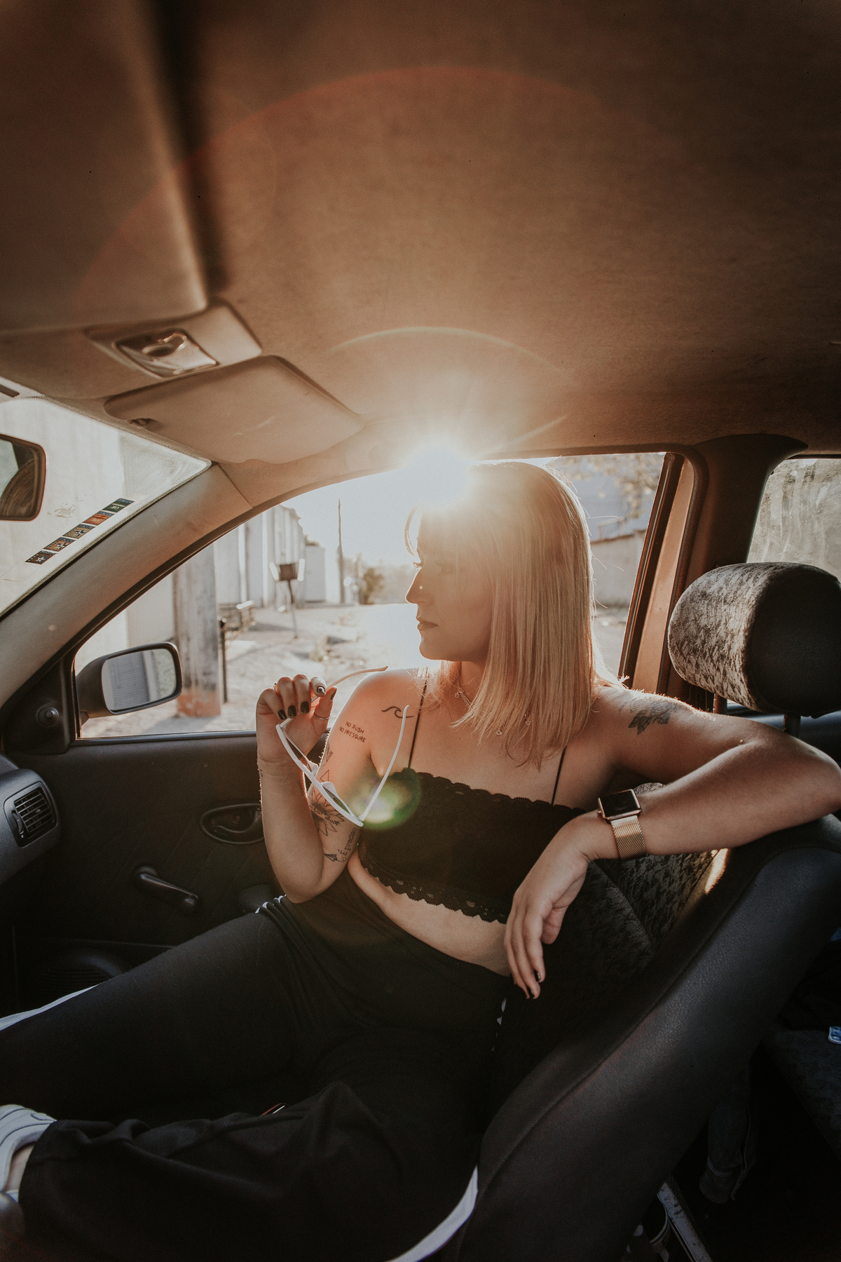 ensaio feminino em betim dentro do carro com uma inspiração de look com jaqueta corta vento, calça pantalona e oculos de sol retro