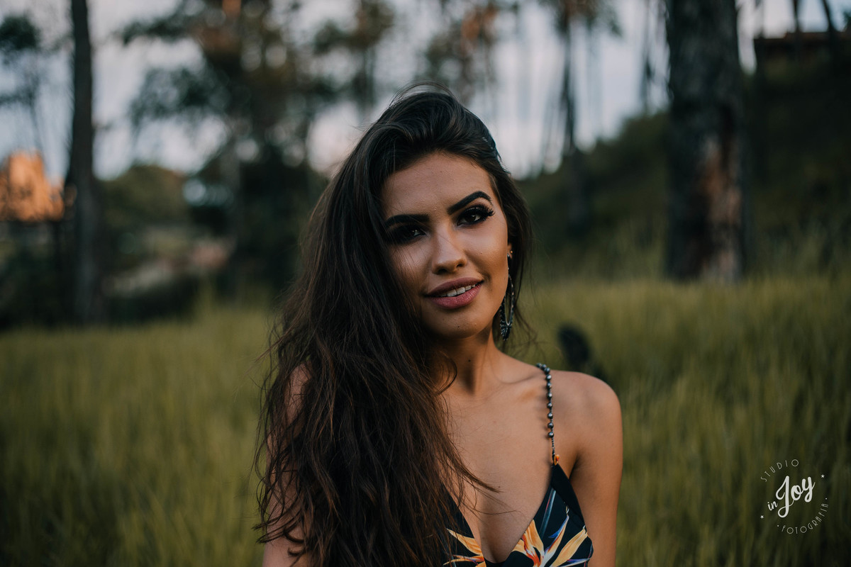 Alicia Bethania sorrindo para a camera em uma fotografia no por do sol