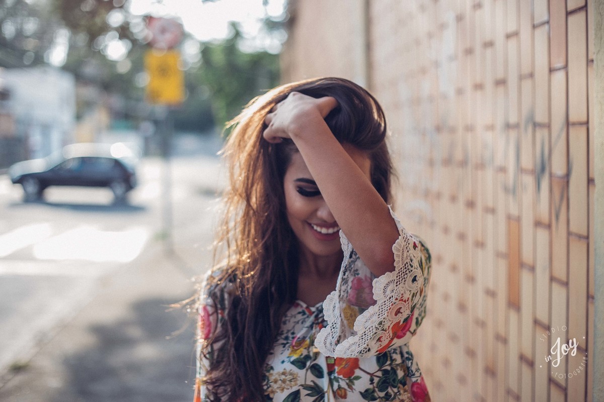 Fotografia de moda em que a modelo está mexendo no cabelo e caminhando pela rua