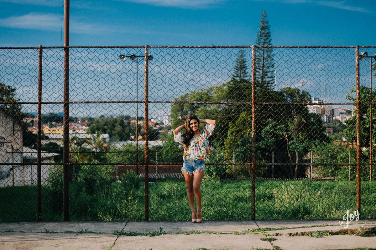 Modelo escorada na frente de uma cerca de telas