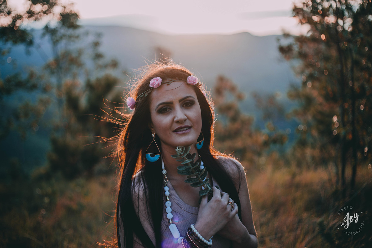 Modelo segurando uma flor perto do rosto em um retrato feminino no alto da montanha