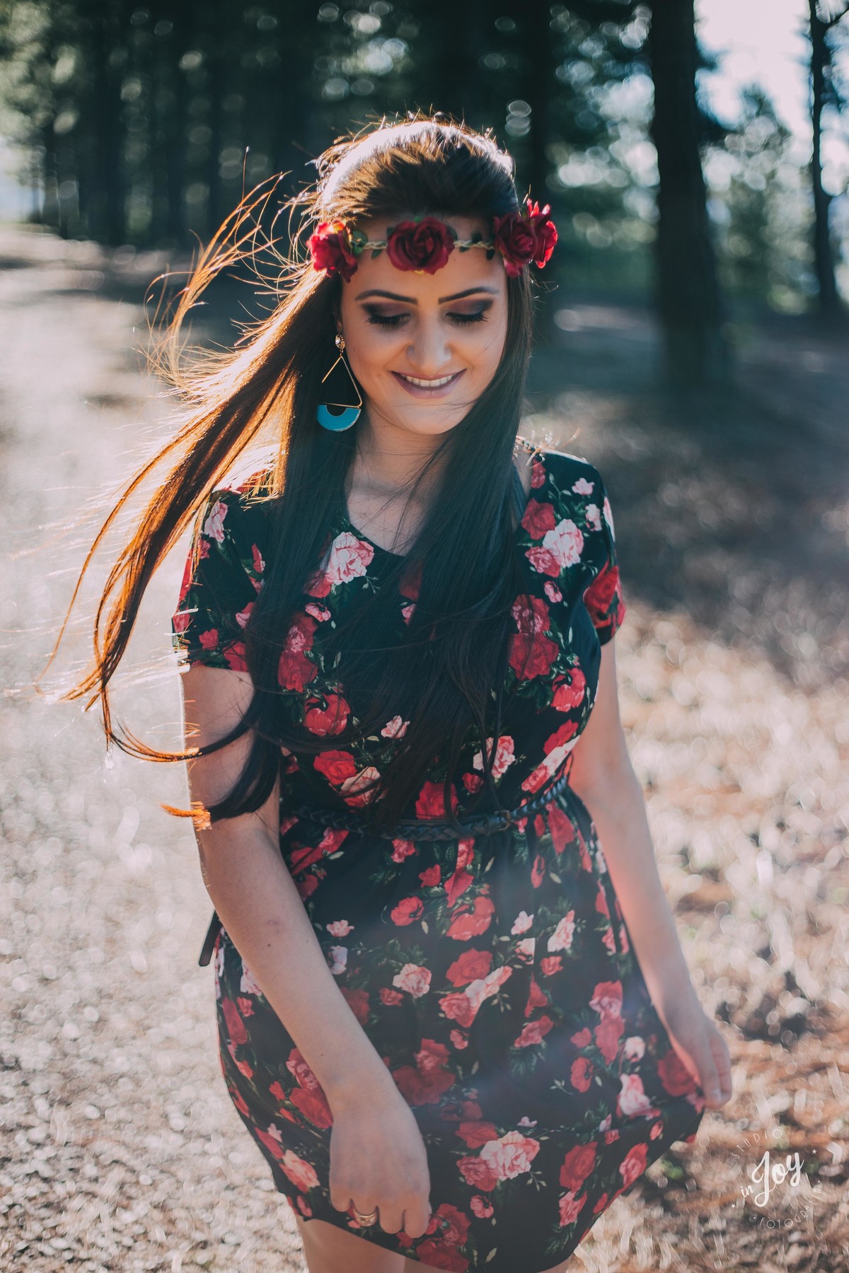 modelo caminhando e sorrindo no por do sol usando uma coroa de folhes e um vestido florido em macacos mg