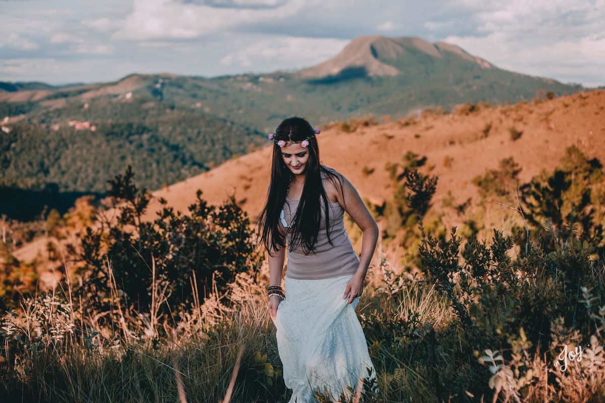 modelo caminhando pela montanha em Macacos MG no por do sol e ao fundo tem varias montanhas