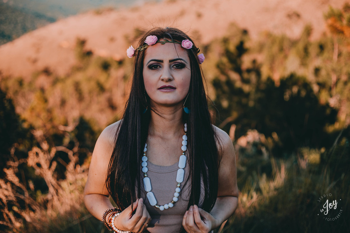 retrato feminino em que a modelo esta segurando os cabelos e olhando para camera usando uma tiara de flores na cabeça