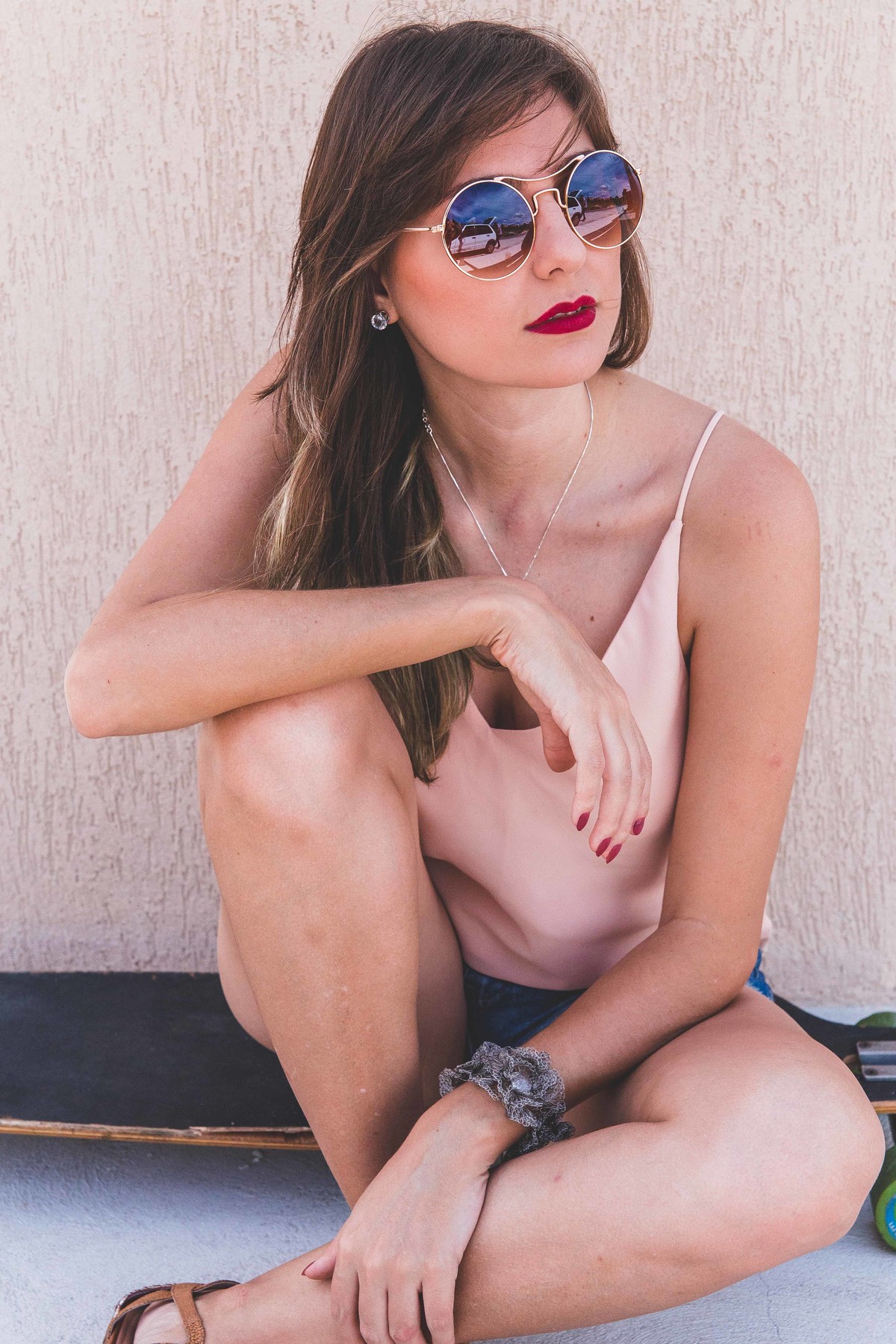 ensaio feminino em betim em que a modelo esta sentada encima de um longboard com o braço encima do joelho e olhando para a paisagem