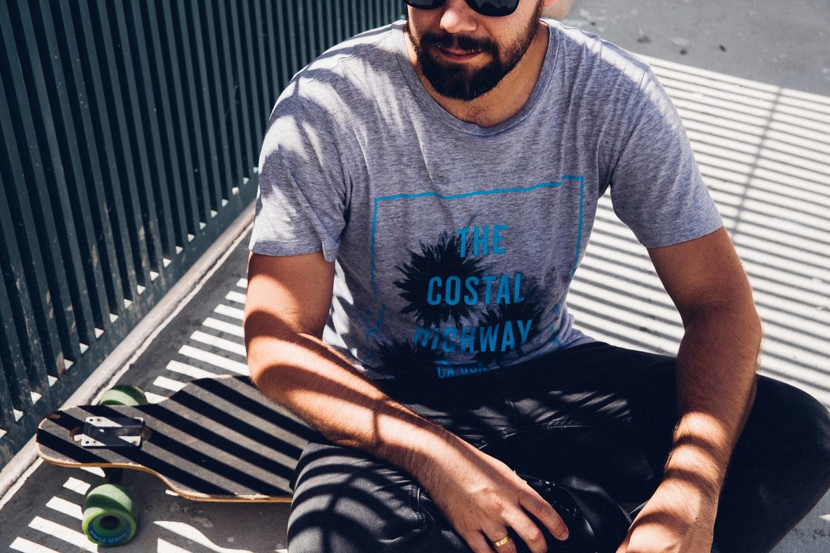 Ensaio masculino com luz de grade no modelo sentado em um longboard em Betim