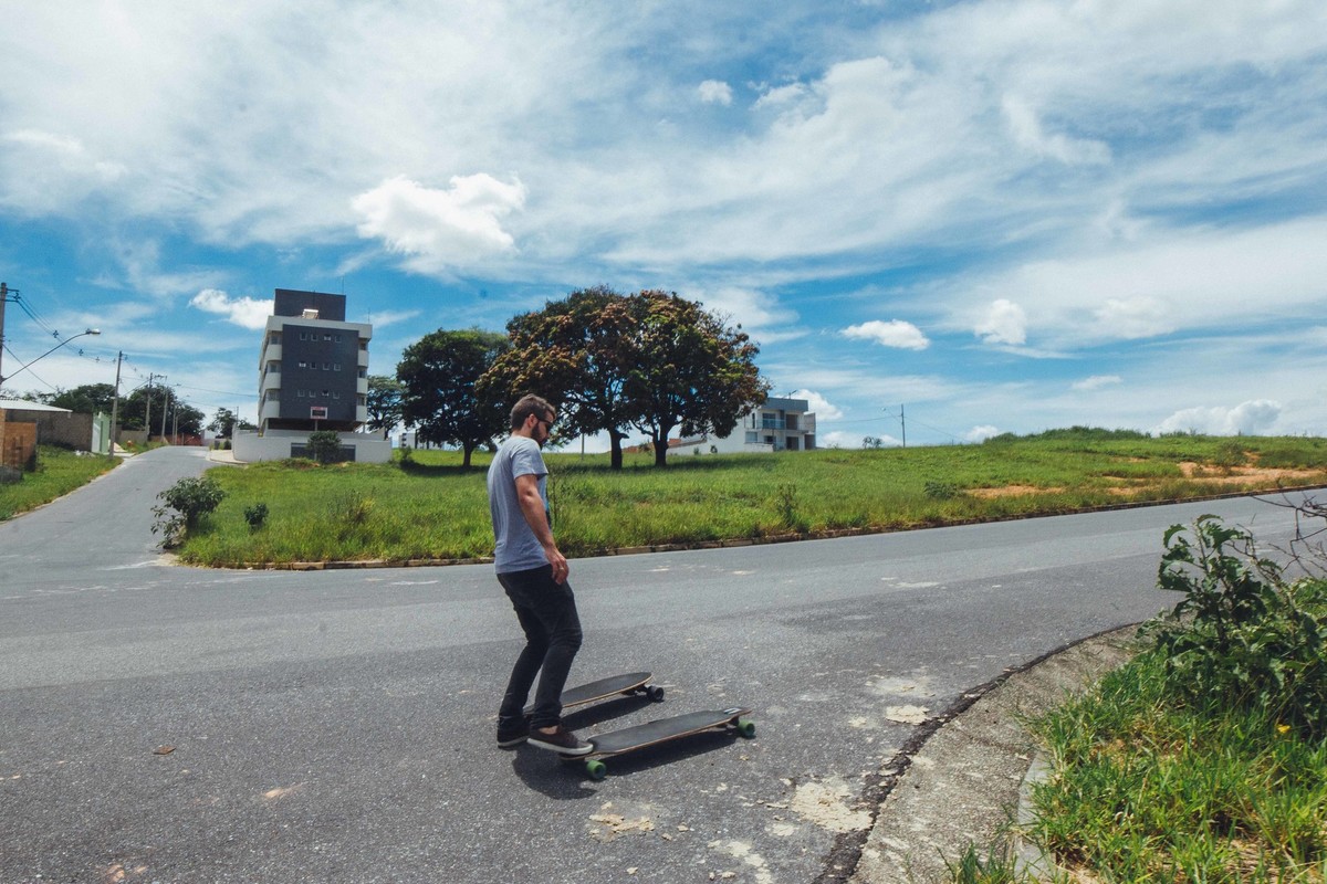 imagem de um homem andando de long board em dia de sol
