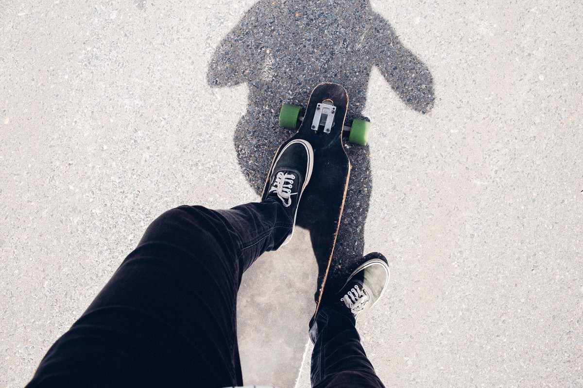 Recorte criativo de uma fotografia que o modelo está com pe encima do longboard usando um tenis vans