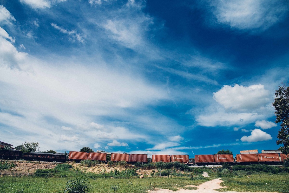 fotografia de um trem de carga passando na linha e um cel azul bem bonito ao fundo