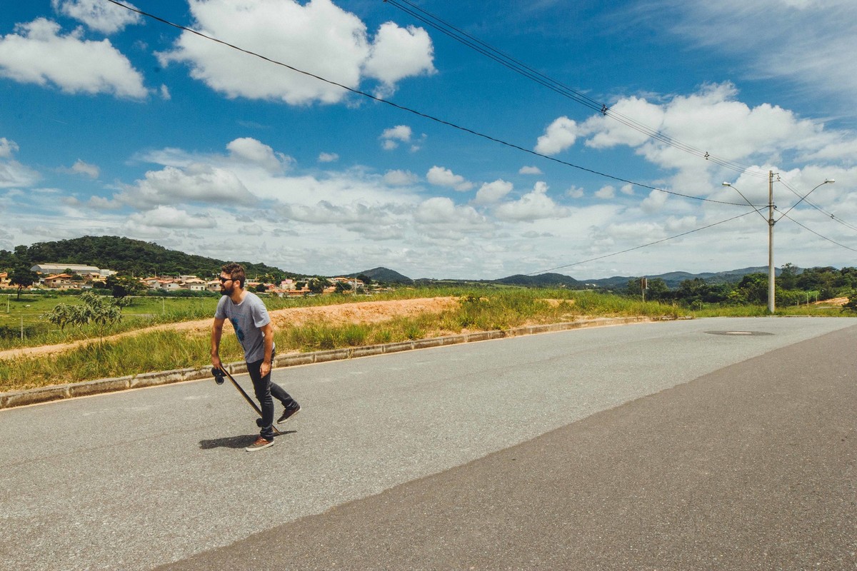 imagem de um homem preparando para andar de long board em dia de sol
