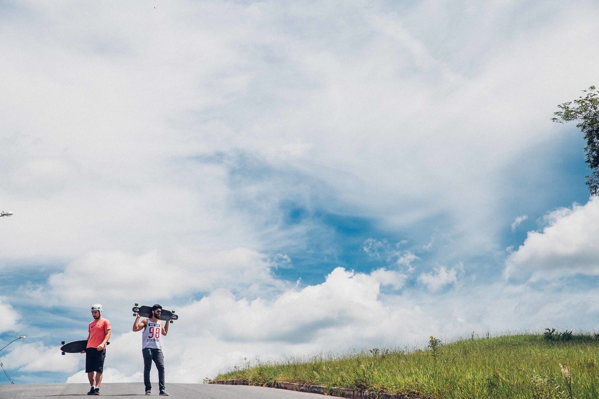 ensaio fotografico em que os modelos estão segurando o longboard nas mãos