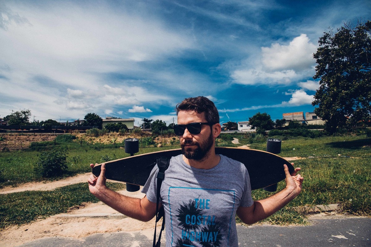 retrato fotografico em que o modelo esta com um longboard nas costas