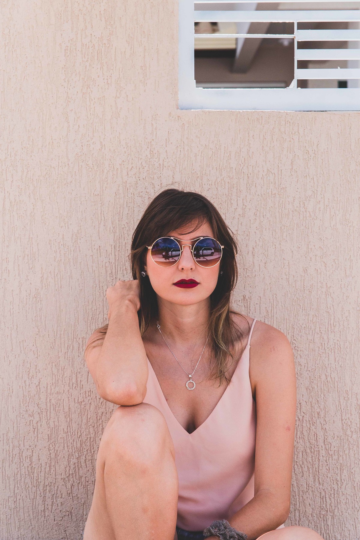 Ensaio feminino em Betim em que a mulher esta sentada encima de um long board e olhando para a camera com um oculos escuro