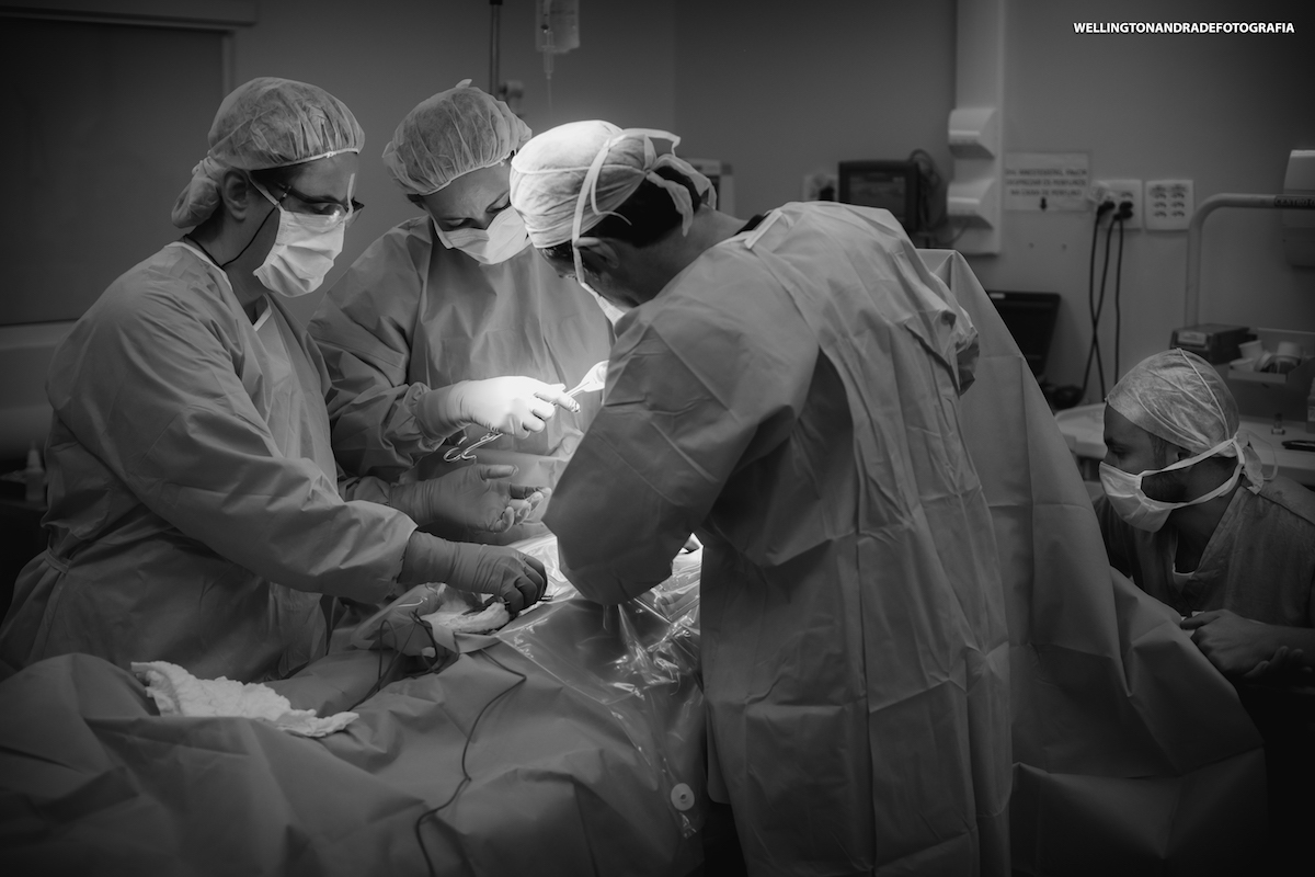 equipe médica dentro do centro cirurgico realizando uma cesariana, fotógrafo de parto faz o registro do momento em que a equipe médica realiza um parto cesariana