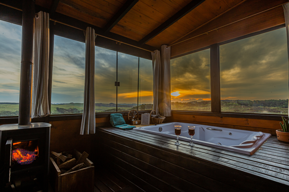 Lareira e uma banheira e uma vista para a natureza em Vista do Vale Chalés