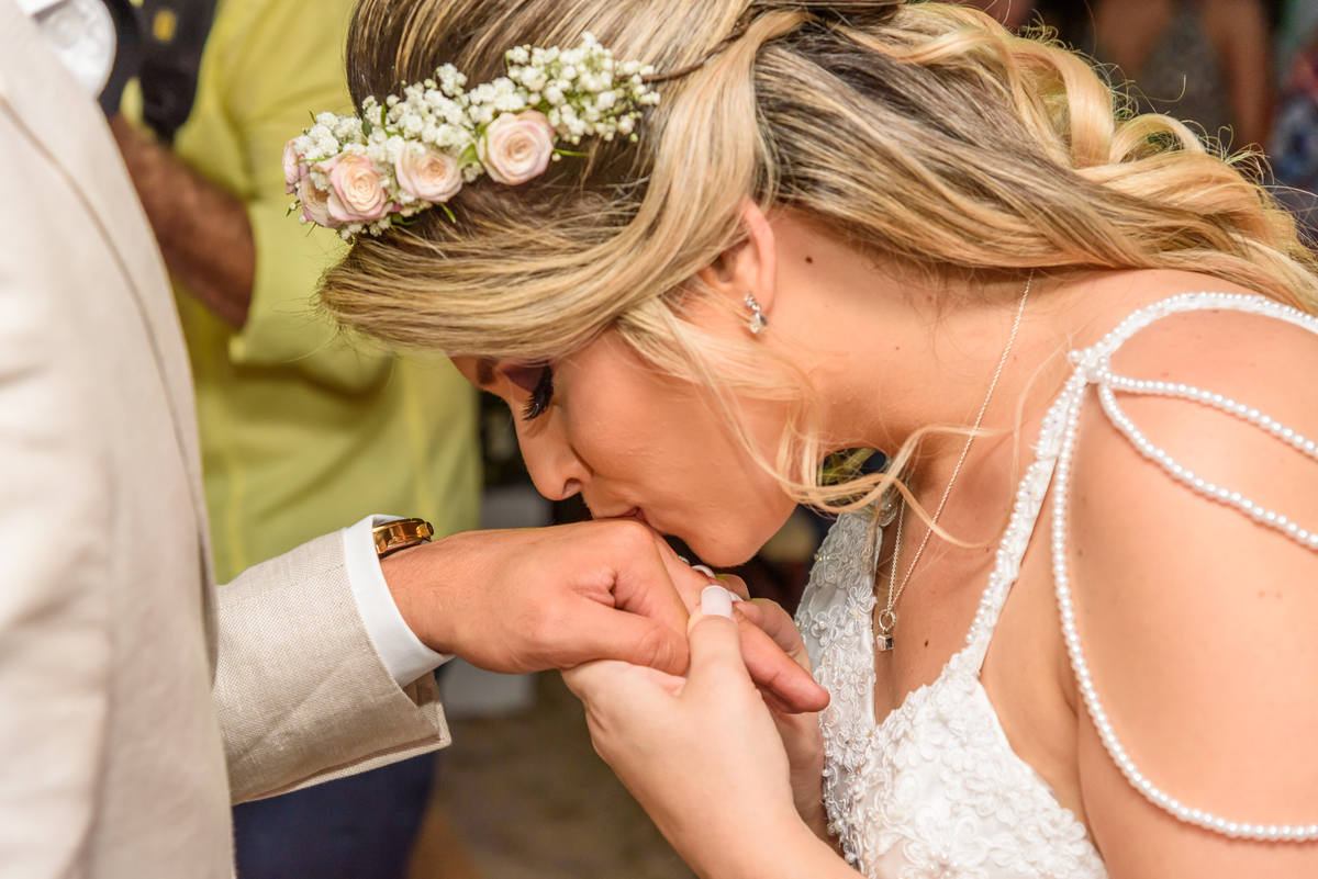 Noiva beija a aliança do noivo durante a celebração do casamento na praia no quiosque harmonia, Niterói - RJ