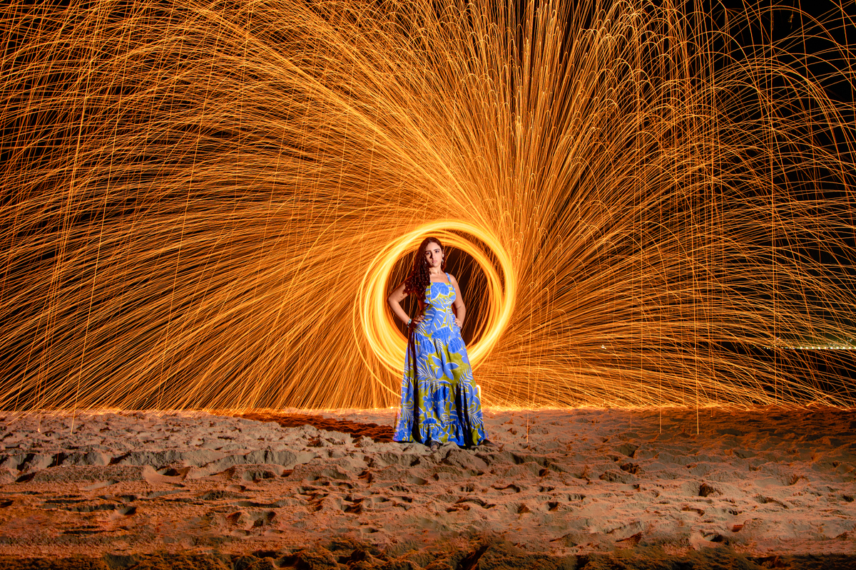 Fotografia de debutante usando a técnica de lightpaint na praia com vestido azul, Rio de Janeiro - RJ