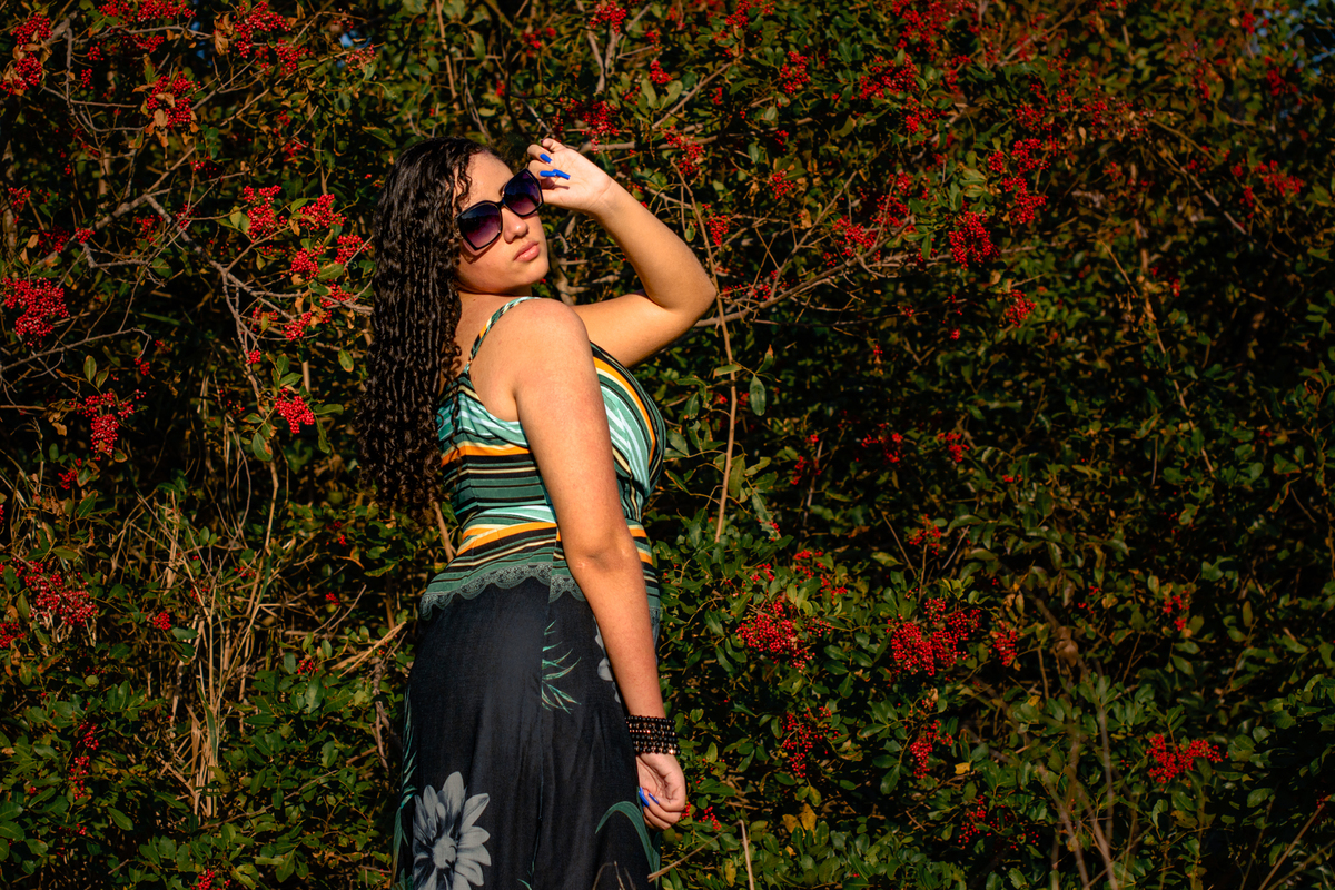 fotografia da debutante Milena de costas segurando os óculos escuro