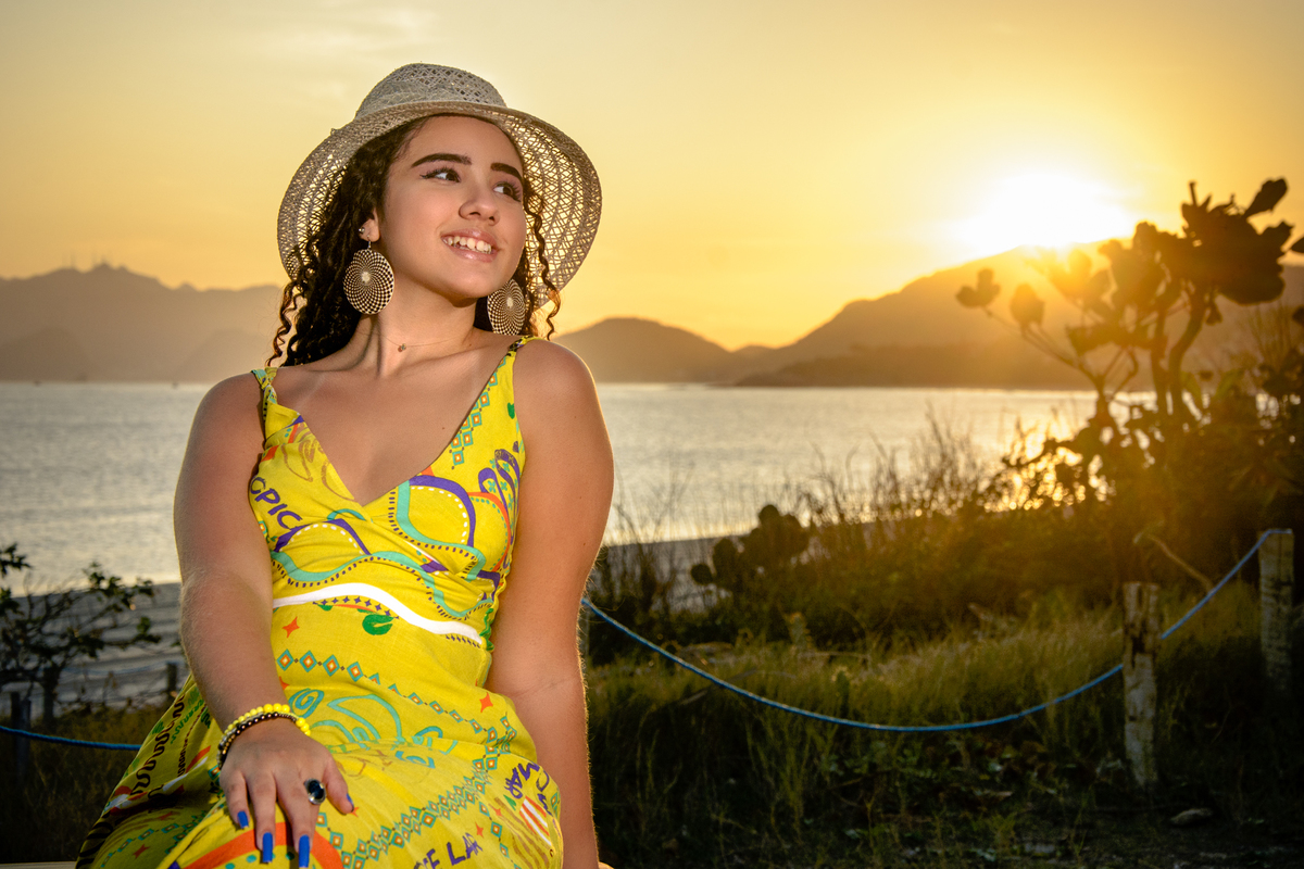 Sorriso da debutante com chapéu ao por do sol na praia de Camboinhas, Niterói - RJ