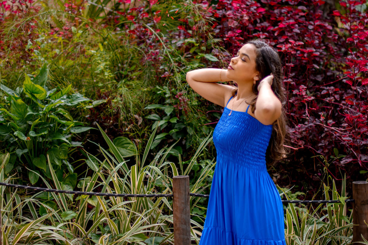 Debutante com vestido azul ao sol com folhas ao fundo, Niterói - RJ