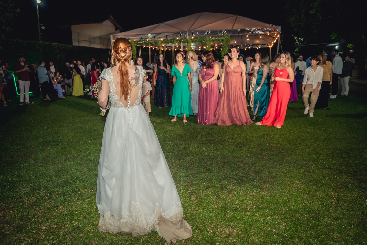 noiva preparada para jogar o buquê com convidados ao fundo na recepção na festa de casamento no campo no sitio na barra da tijuca - RJ