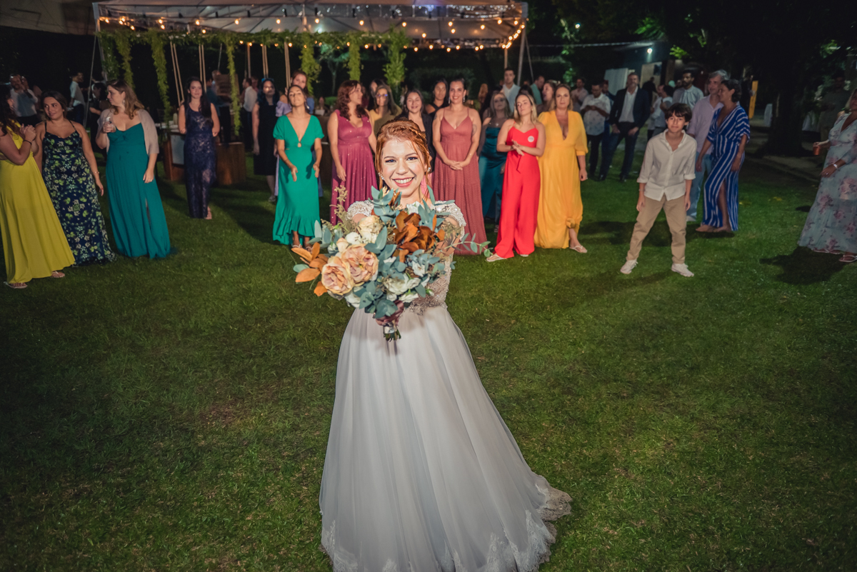 noiva preparada para jogar o buquê com convidados ao fundo na recepção na festa de casamento no campo no sitio na barra da tijuca - RJ