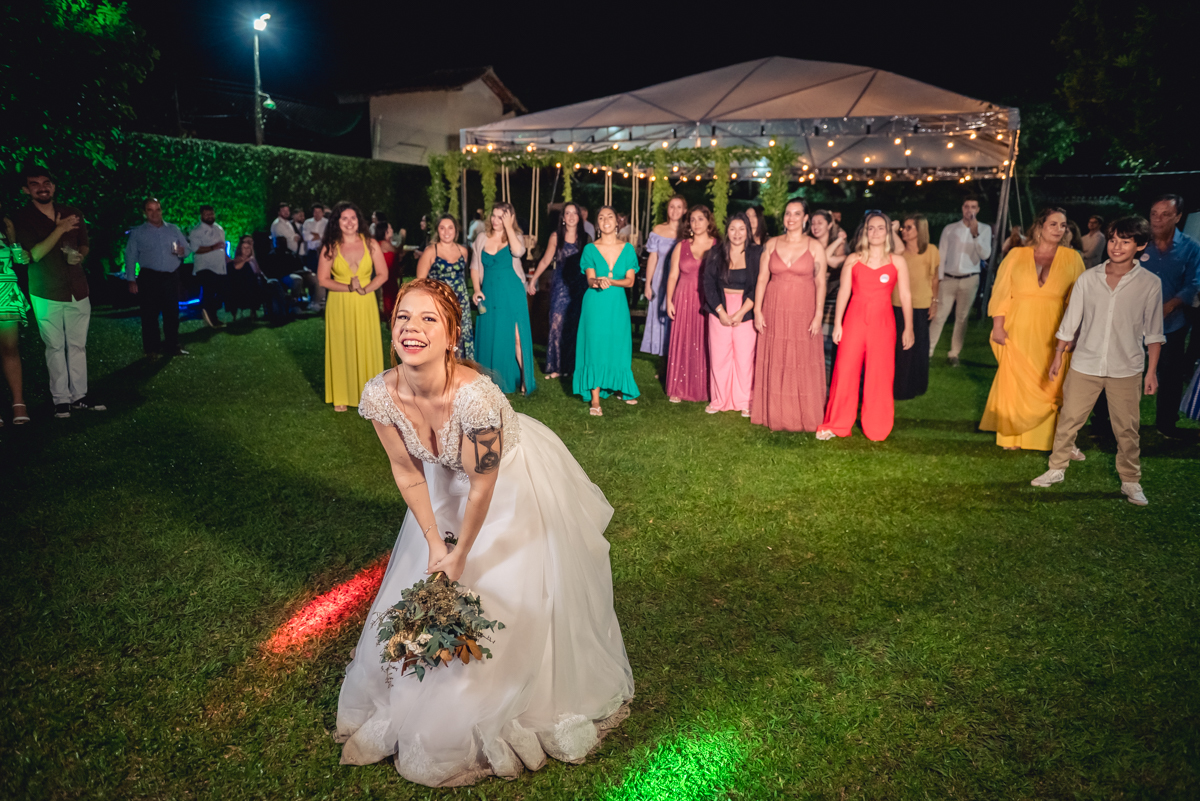 noiva preparada para jogar o buquê com convidados ao fundo na recepção na festa de casamento no campo no sitio na barra da tijuca - RJ