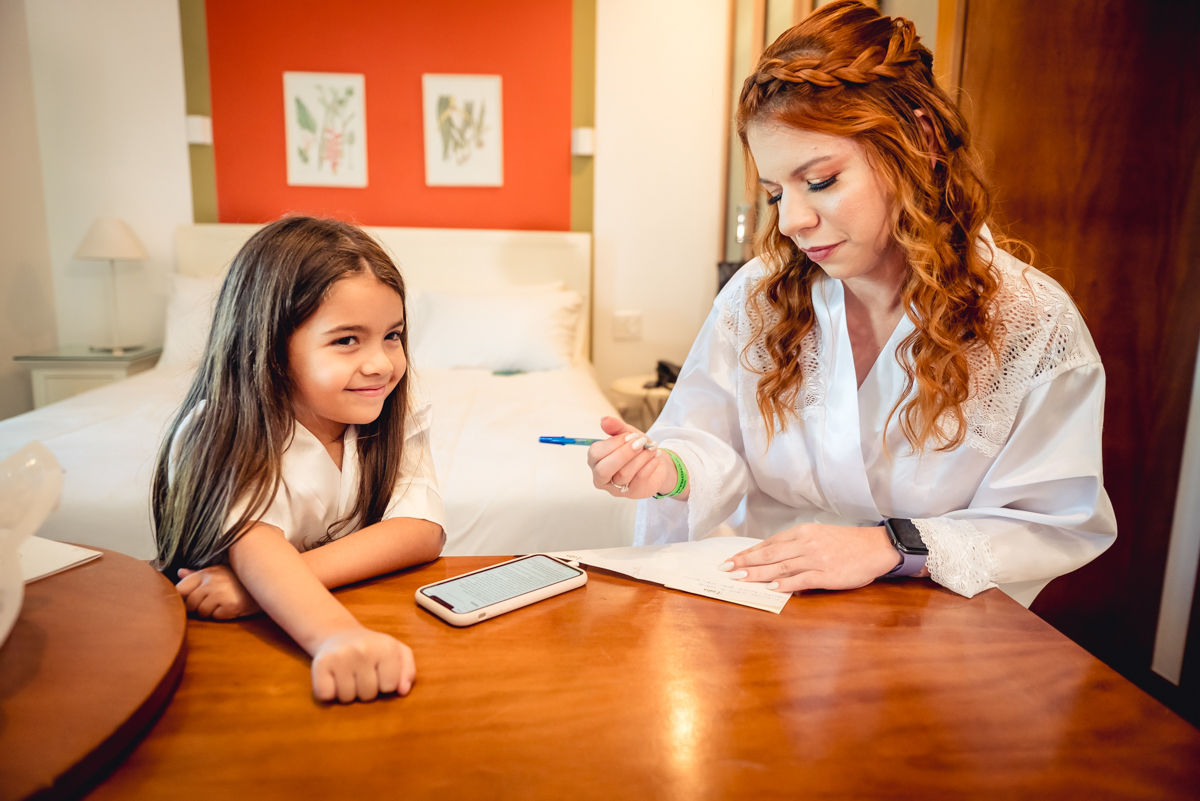 noiva escrevendo o depoimento ao lado da daminha sorrindo no making of no hotel Wyndham rio Barra - RJ