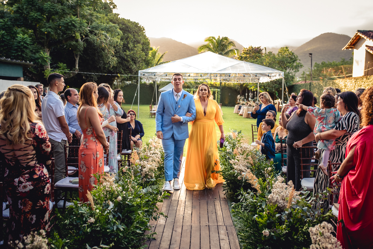 Entrada do noivo com terno azul e sua mãe com vestido amarelo para a cerimonia de casamento no sitio da paz, Barra da Tijuca - RJ
