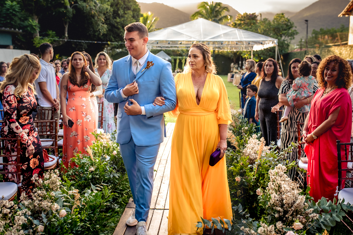 Entrada do noivo com terno azul e sua mãe com vestido amarelo para a cerimonia de casamento no sitio da paz, Barra da Tijuca - RJ