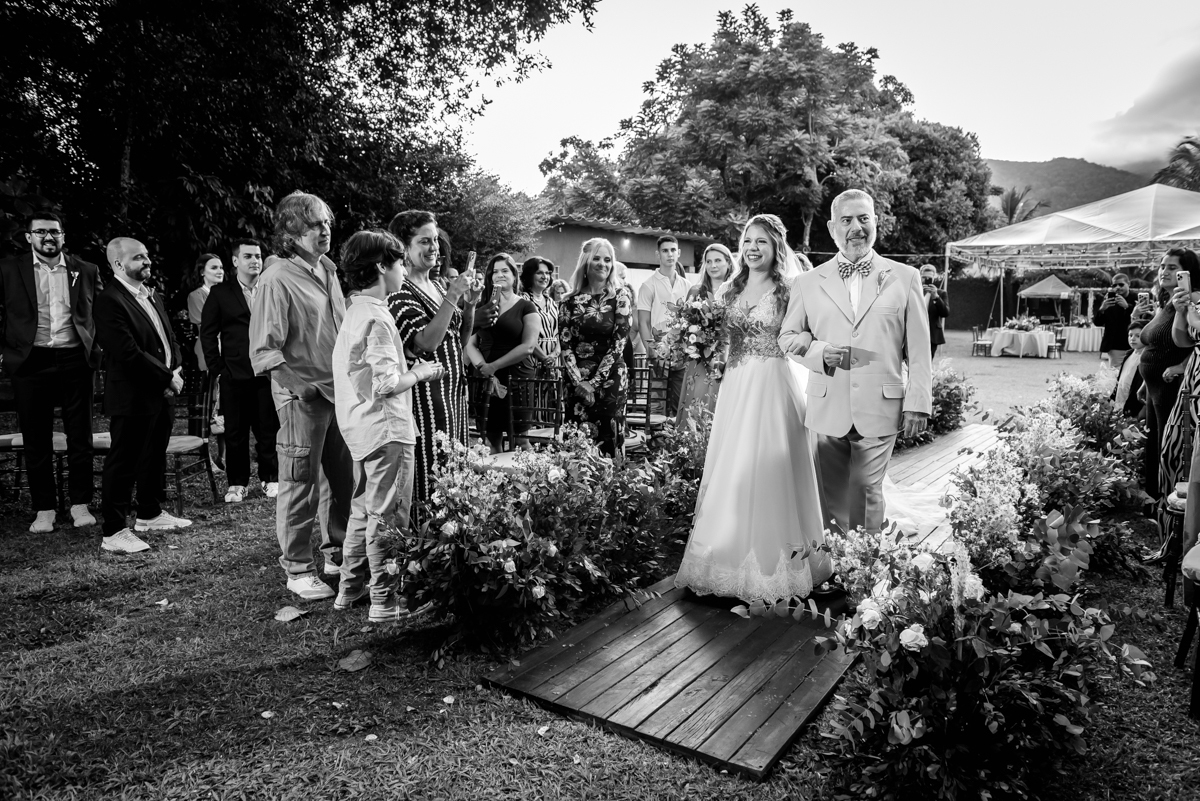 fotografia em preto e branco da entrada da noiva Caroll com seu lindo vestido para a cerimonia de casamento no sitio da paz, barra da Tijuca - RJ