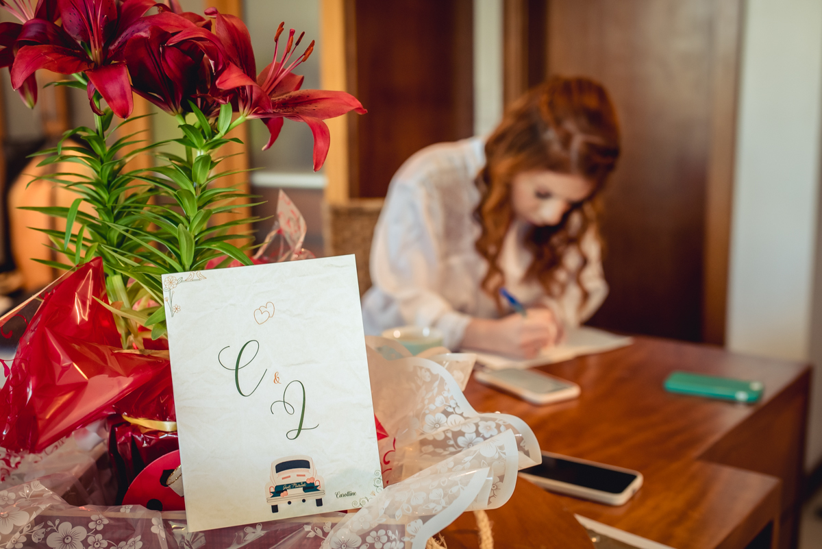 convite de casamento no making of no hotel com a noiva escrevendo o depoimento ao fundo na barra da Tijuca - RJ