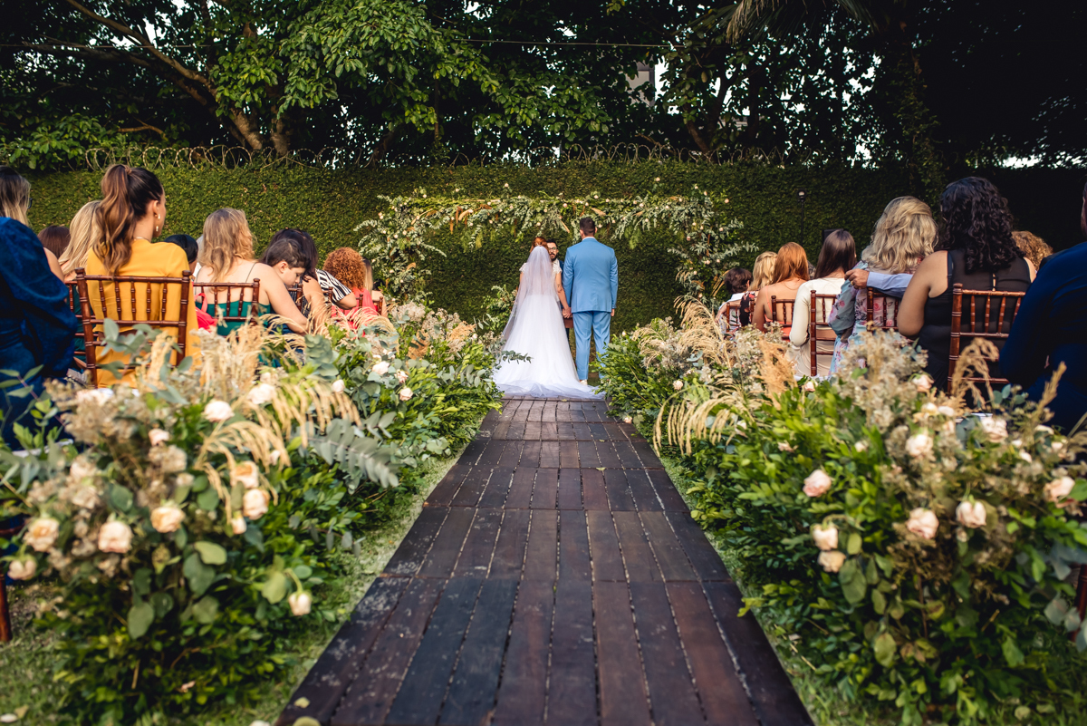 noivos caroll e Lucas de costas durante a celebração do casamento de dia no sitio 