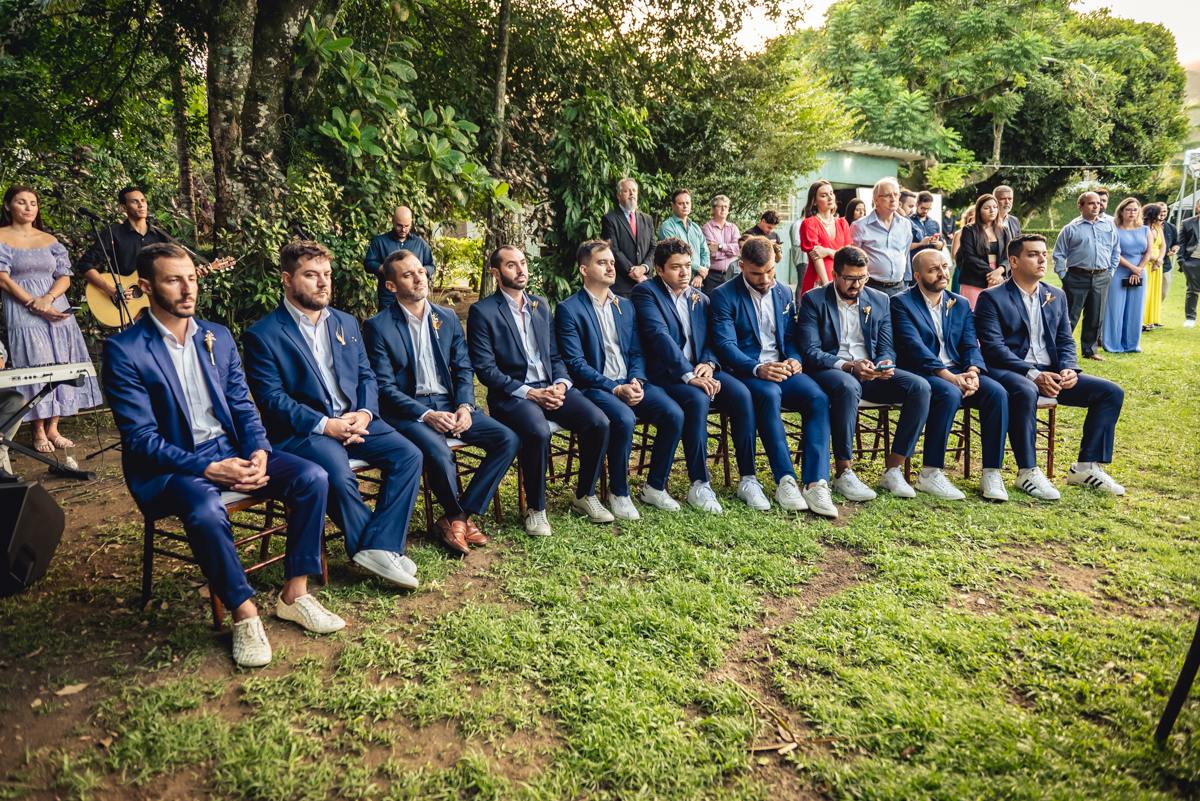 padrinhos sentados ao lado do púlpito durante a celebração do casamento de dia de caroll e Lucas no sitio da paz na barra da Tijuca - RJ