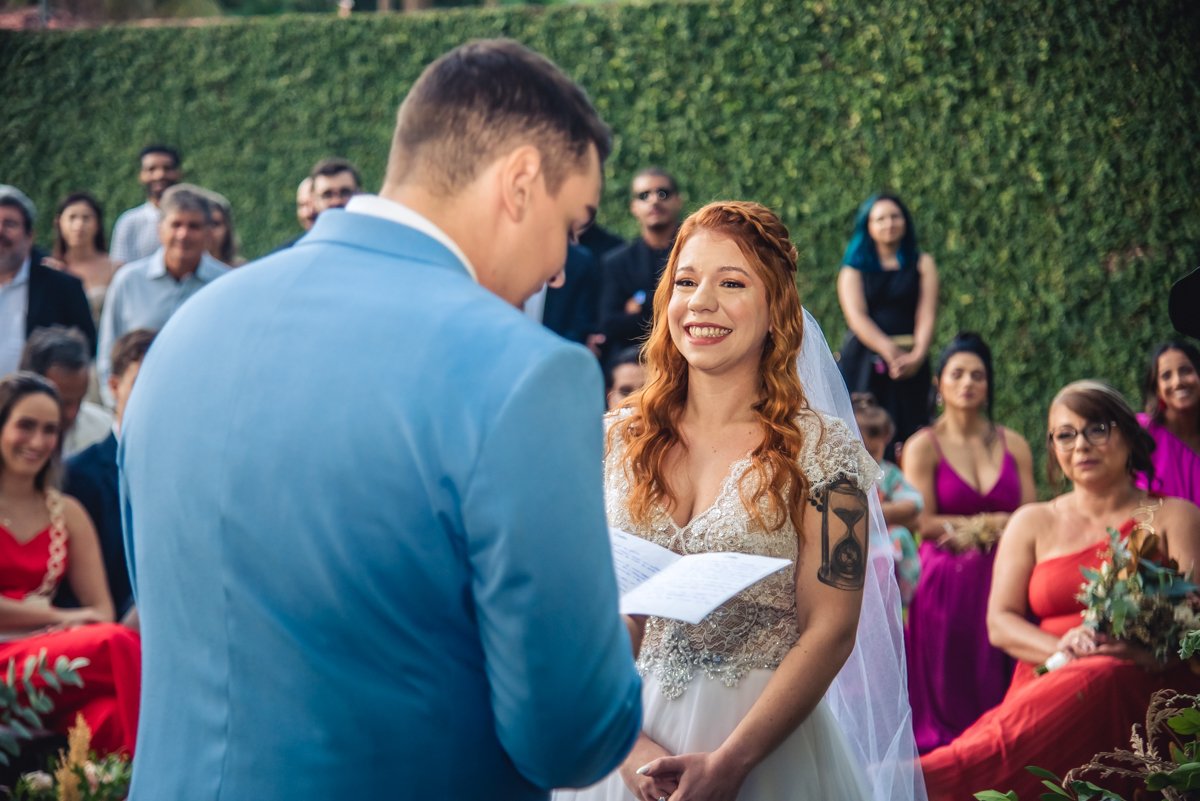 noiva sorri durante os votos realizados pelo noivo durante a celebração do casamento de dia ao fim da tarde no sitio da paz - RJ