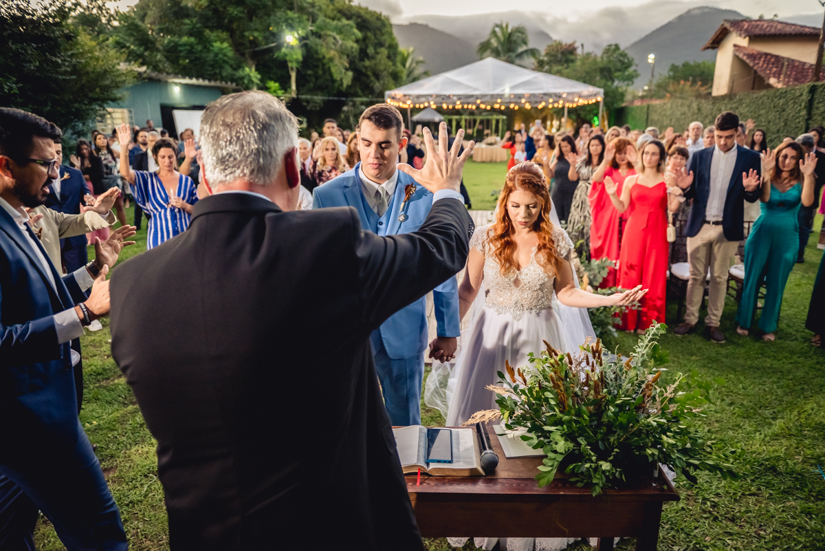 pastor da a benção ao casal durante a cerimonia de casamento de dia no fim da tarde no sitio da paz com a presença de todos os convidados na barra da Tijuca - RJ