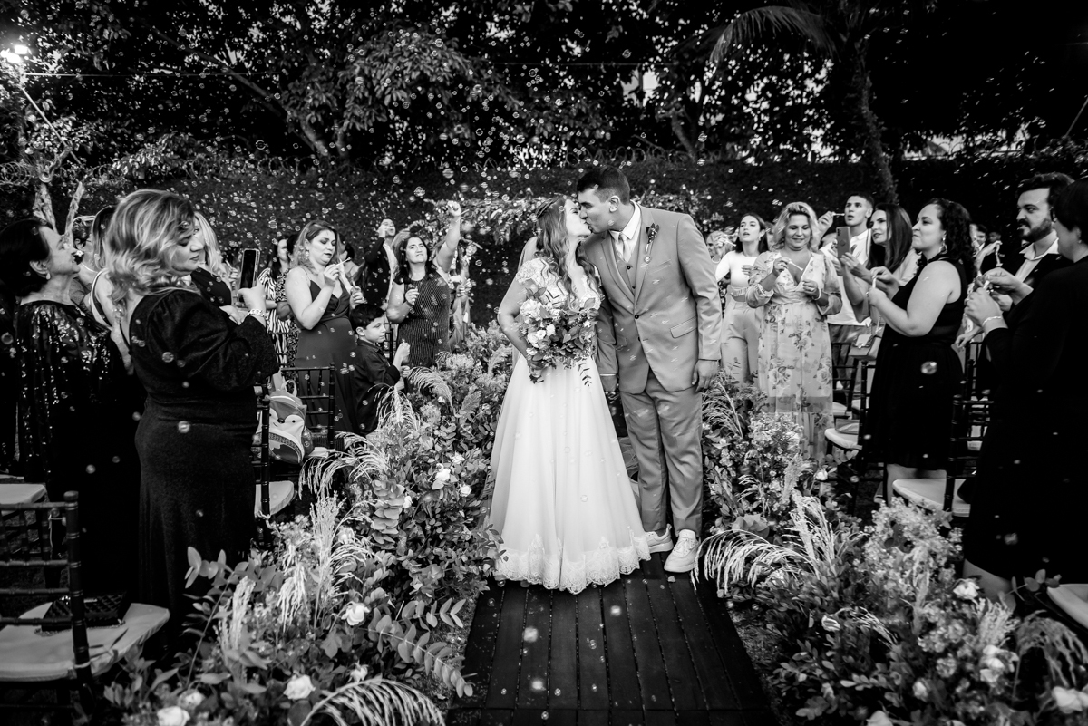 beijo dos noivos em preto e branco com bolhas de sabão ao fundo após a cerimonia de casamento no sitio no fim de tarde na barra da Tijuca - RJ