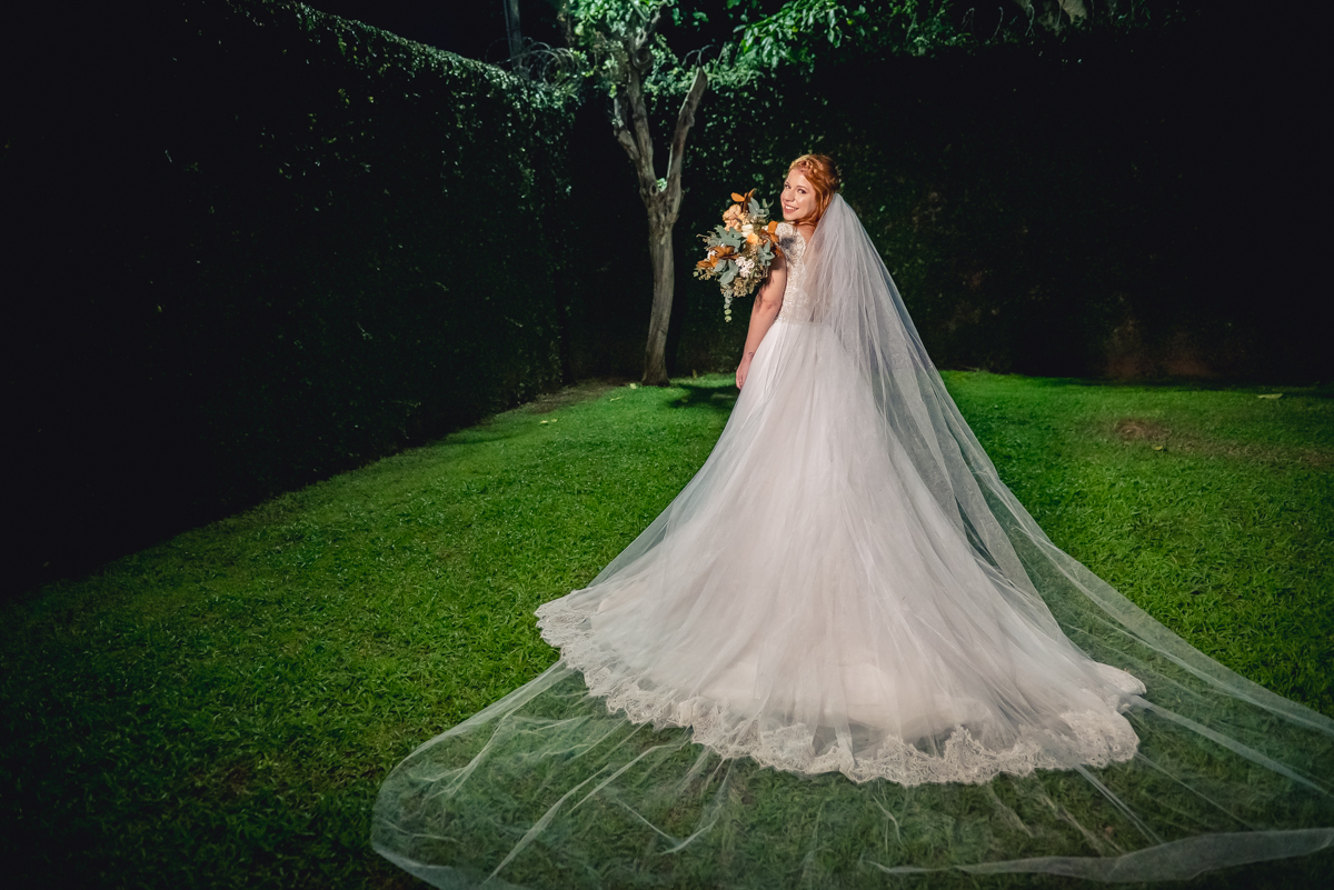 noiva de costas com vestido aberto e véu aberto com buquê no casamento no sitio na barra da Tijuca - RJ