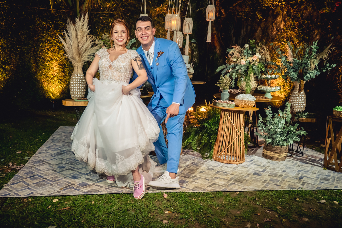 noivos mostrando o tênis na noiva com a decoração da mesa do bolo ao fundo no casamento no campo no sitio na barra da tijuca - RJ