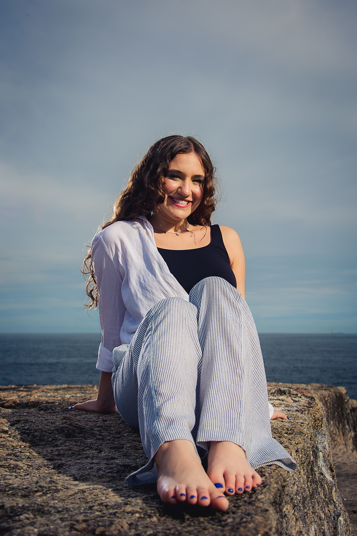debutante sentada, sorrindo com mar ao fundo e iluminação lateral