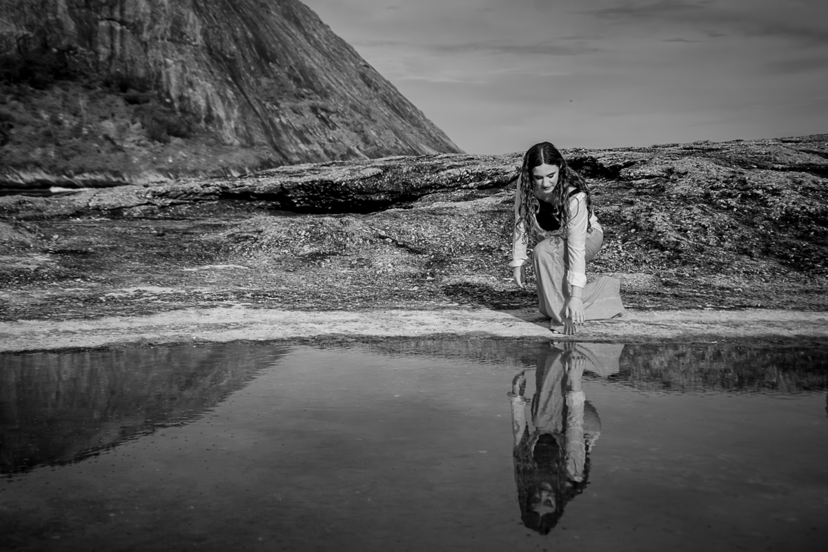 debutante tocando a agua e vendo o seu reflexo na praia de Itacoatiara
