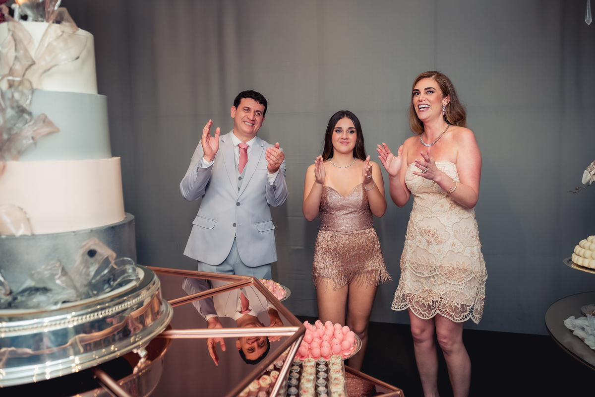 foto com a debutante isabella no momento dos parabéns na mesa do bolo na casa das canoas - São Conrado